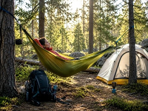 Woman relaxing in green hammock camping