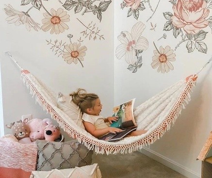 Child reading in indoor fringed hammock