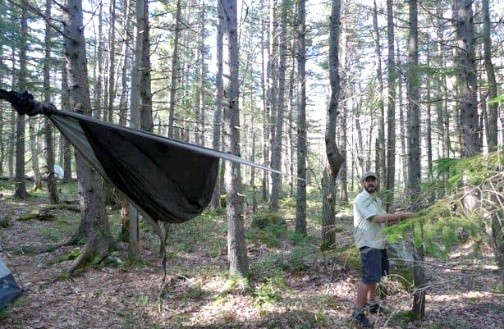 Man setting up hammock in forest