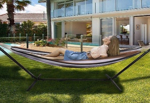 Woman relaxing on hammock stand by pool